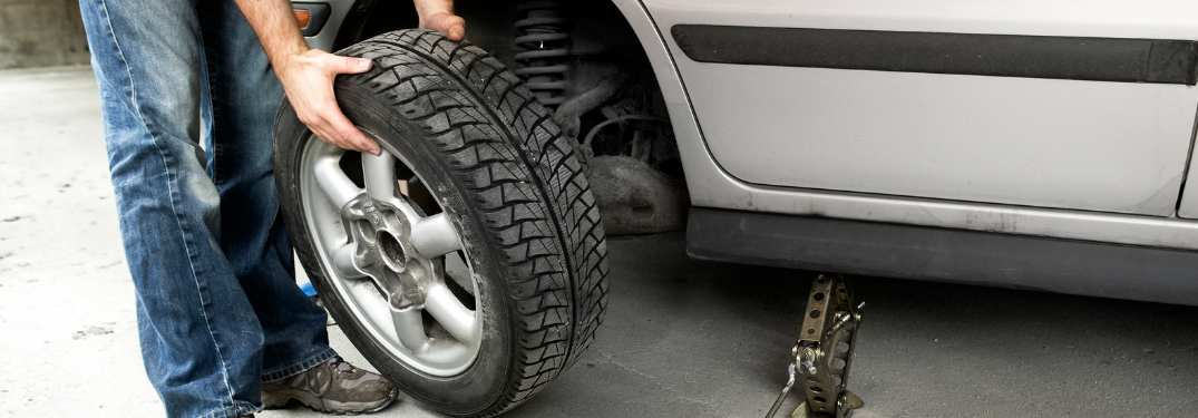 A man checking tire of a vehicle
