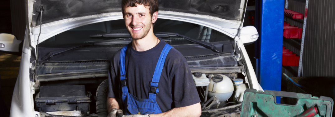 Mechanic posing in front of a car
