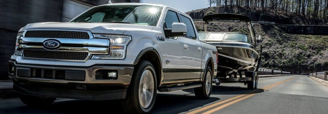 2018 Ford F-150 driving on the road towing a boat