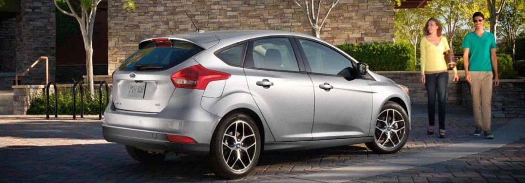 Two people walking towards the 2018 Ford Focus parked on a street