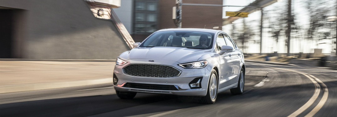 front view of white 2019 ford fusion driving down empty city road