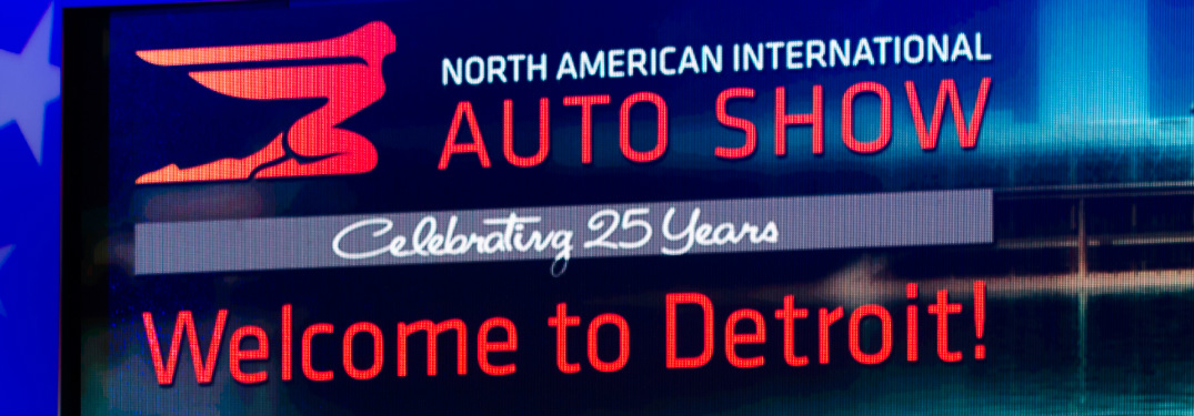 Large Screen with the Caption, "North American International Auto Show, Celebrating 25 Years and Welcome to Detroit!"