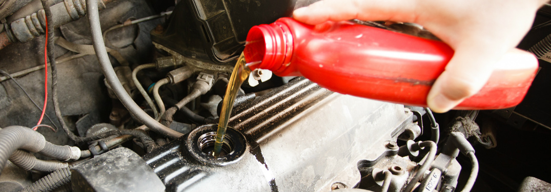 Person Pouring Oil into a Car Engine