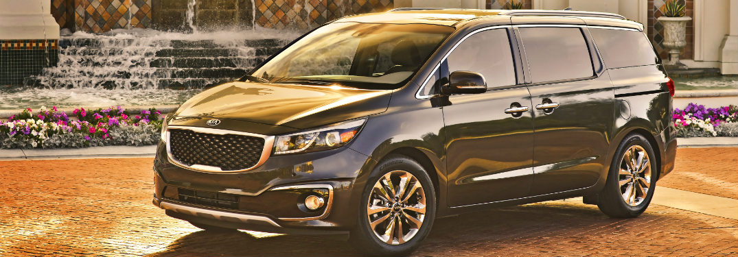 blue 2018 kia sedona on brick road in front of fountain