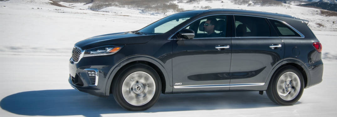 blue 2019 kia sorento driving on snowy trail with mountains behind it