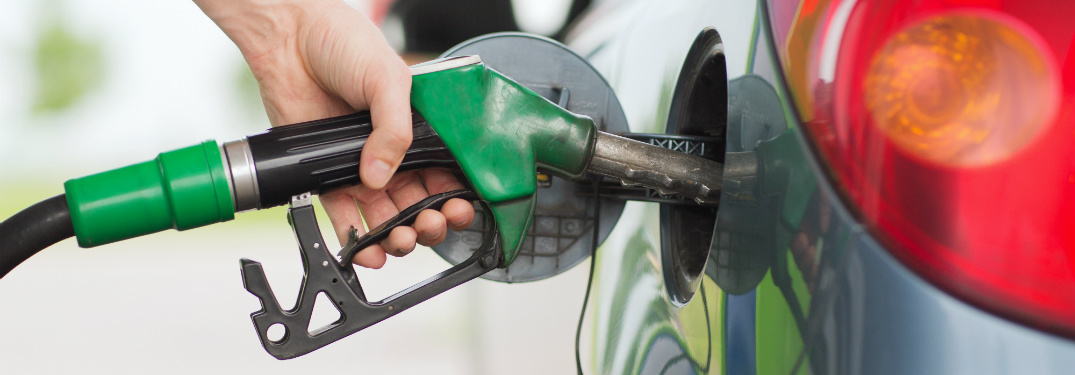 close up of hand holding gas station pump filling up gas tank of car
