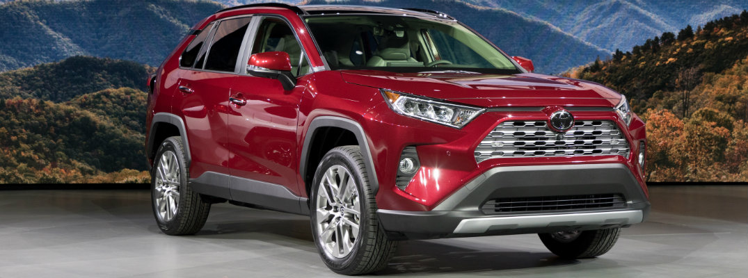 Red 2019 Toyota RAV4 set in front of mountain scene at an auto show