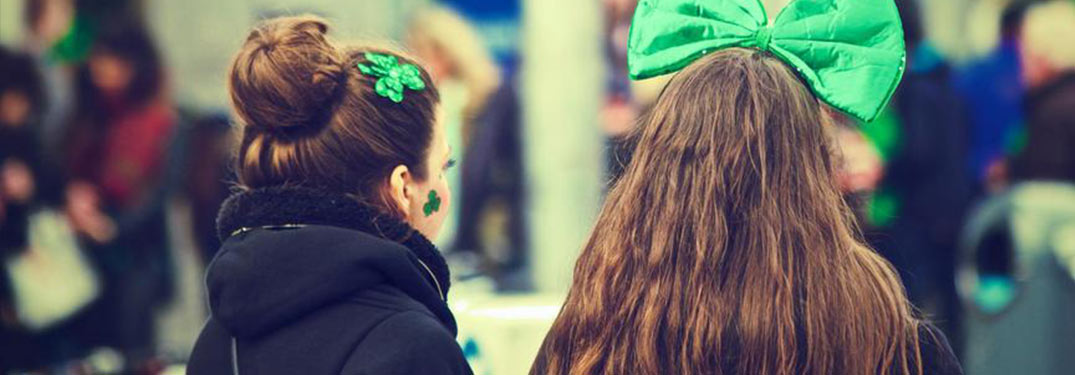 two young women with green headbands for St. Patrick's Day, seen from behind