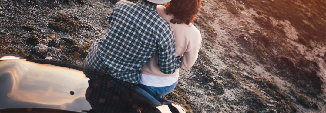 couple sitting on the hood of a car hugging