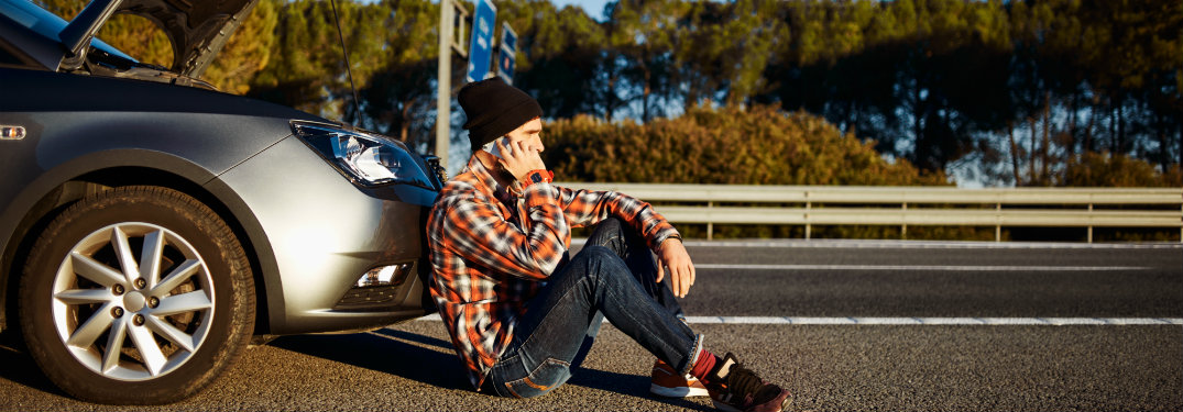 young man with a broken car calling someone