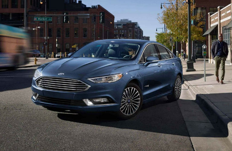 Blue 2018 Ford Fusion pulling away from city curb