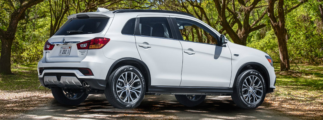 White 2018 Mitsubishi Outlander Sport parked in front of trees in forest