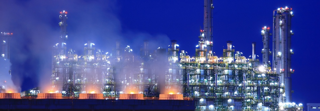 Skyline of an oil refinery at twilight, looking like the backdrop of a Sega Genesis game.