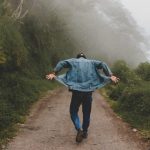 man-walking-on-foggy-trail-flipping-up-ends-of-jean-jacket_b