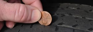 someone using a penny to check the tread of a tire