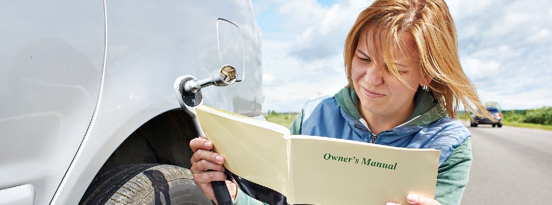 A stock photo of a person reading a vehicle's owner's manual.