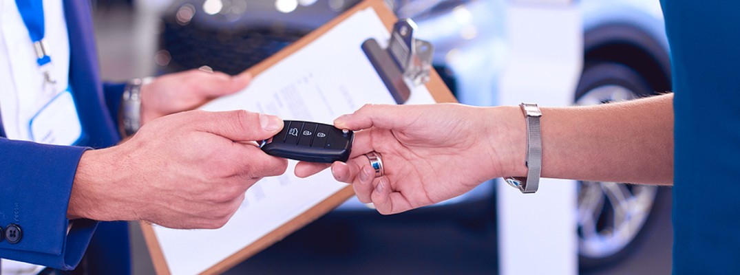 A stock photo of a person handing a new set of keys to another person.