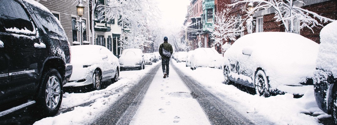 A stock photo of a person walking through snow because their car wouldn't start.