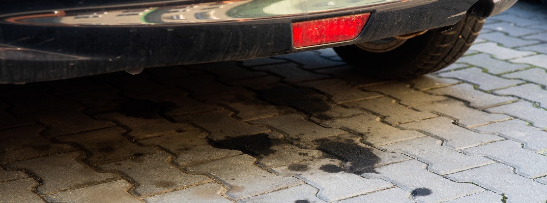 A stock photo of oil spots on a driveway under a car.