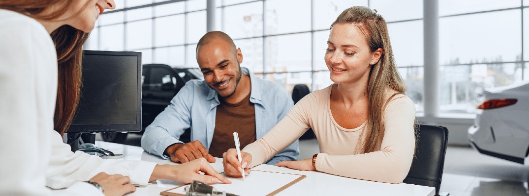 A stock photo of people finishing the paperwork to buy a car.