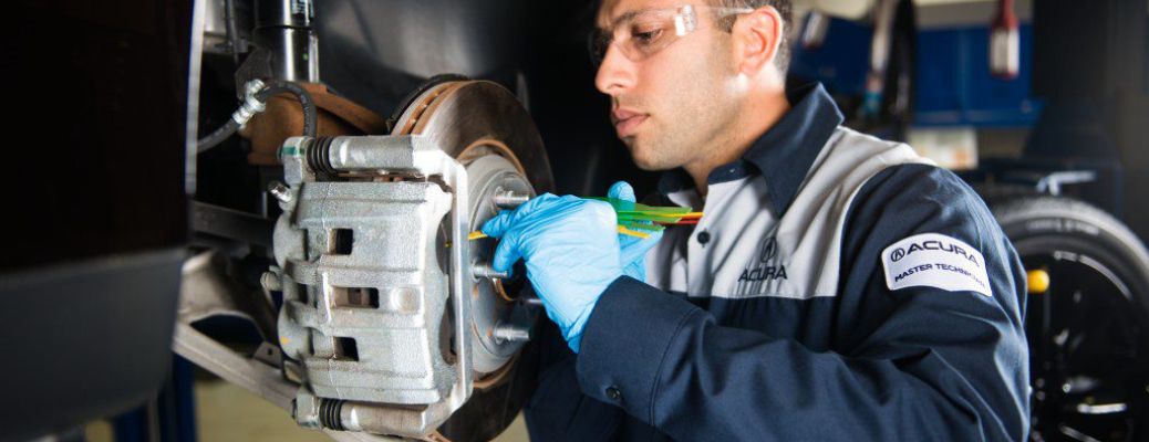 One mechanic is working on the brake system of a car.