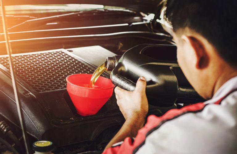 Service technician pouring oil into a funnel