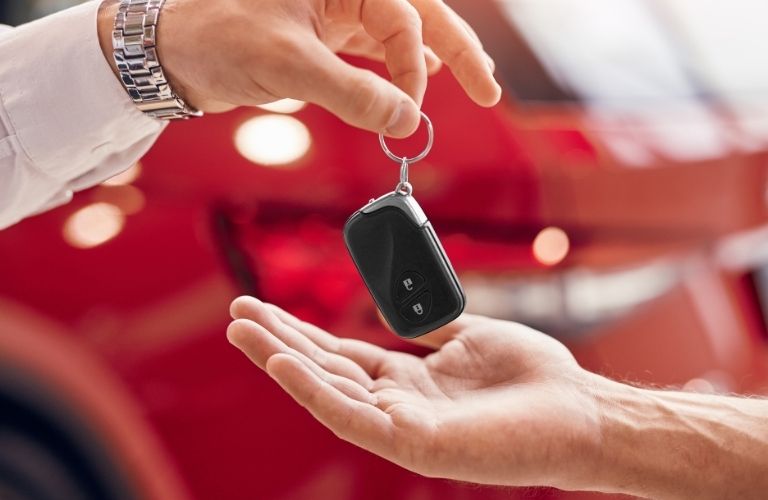 Sales person giving a car key to a buyer