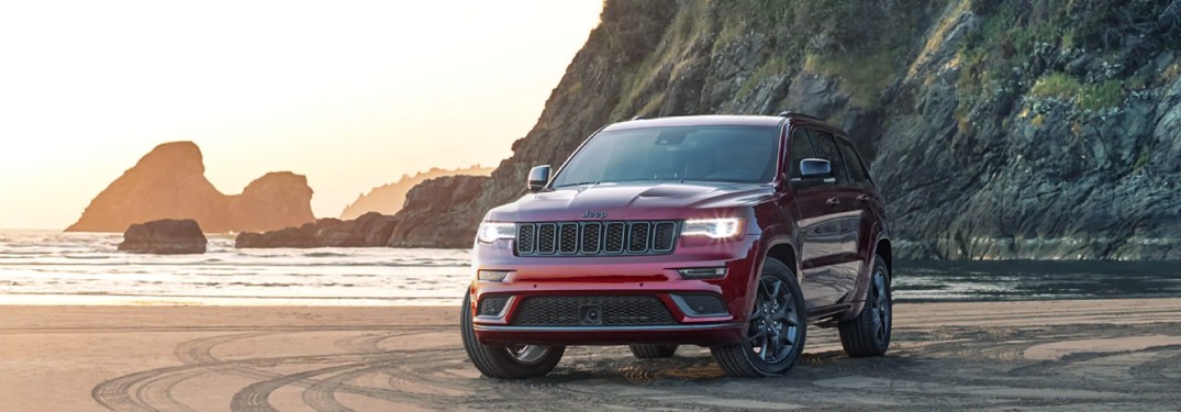 2020 Jeep Grand Cherokee red exterior parked on a beach with cliffs