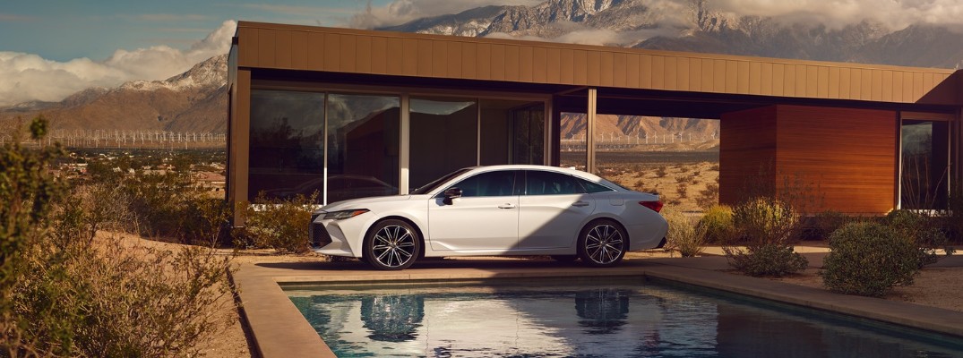 2020 Toyota Avalon in front of a swimming pool near a luxury home near the mountains