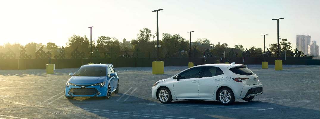 A photo of two 2019 Toyota Corolla Hatchback models in a parking lot.