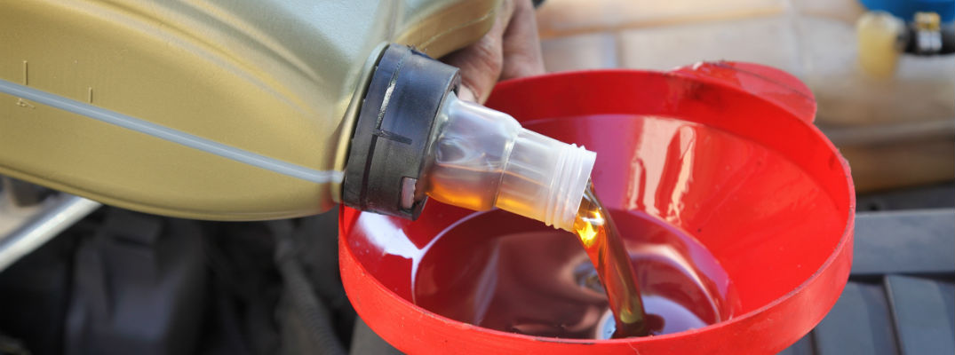 A stock photo of motor being poured into a funnel.