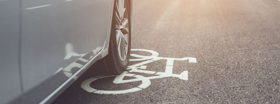 A stock photo of a car driving in a bike lane on a road.
