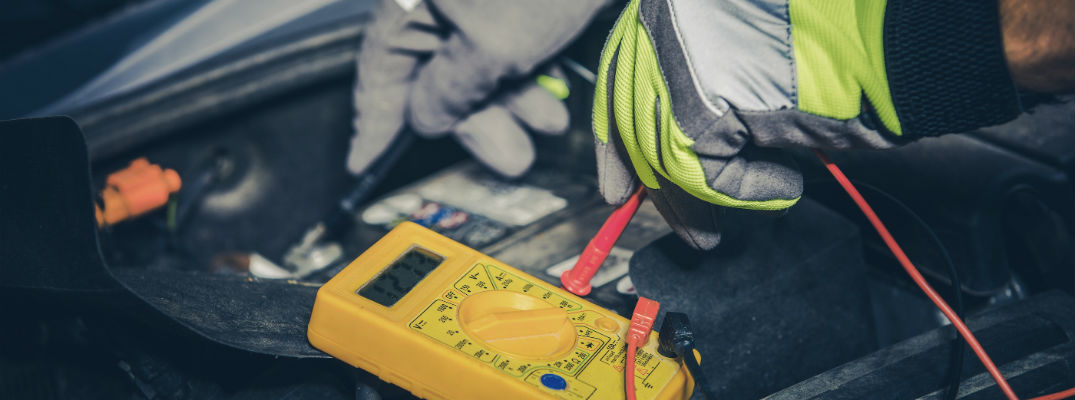 A stock photo of a service technician testing a car's electrical system.