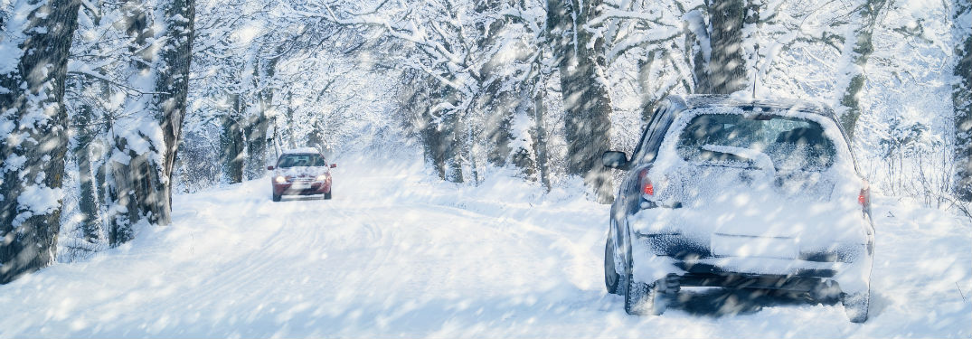two cars driving on road during blizzard
