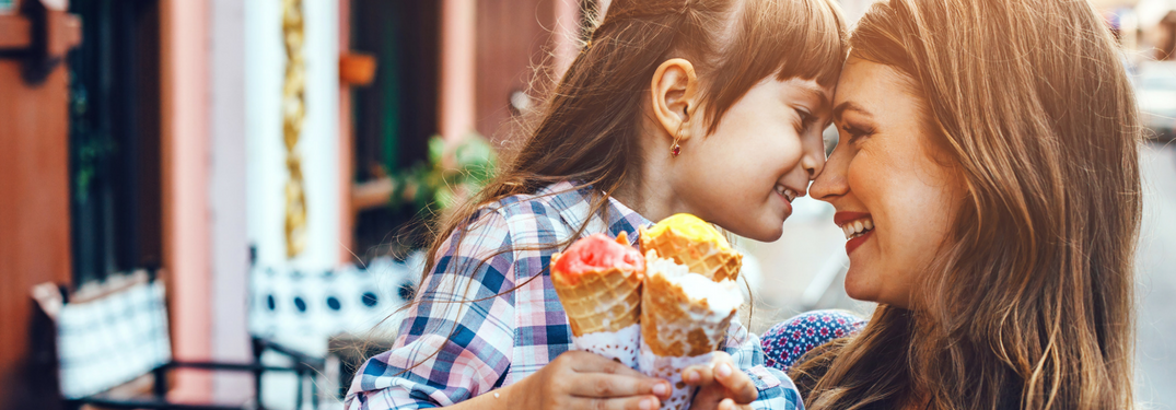 mother and daughter touch noses and hold ice cream