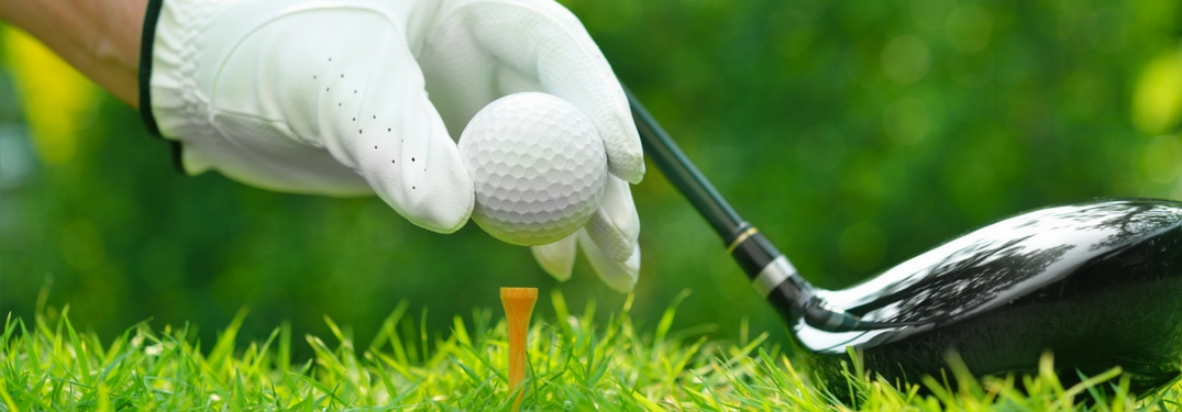 hand putting golf ball on golf tee