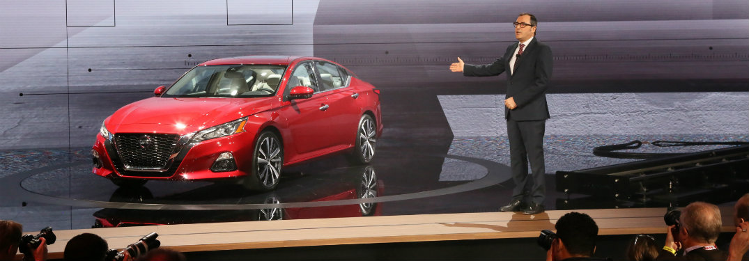 man on stage with red nissan altima