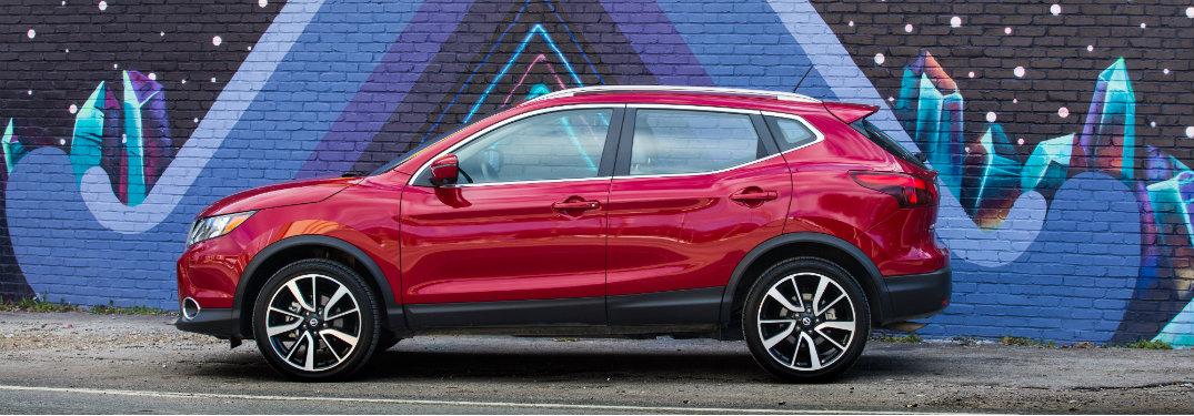 red nissan rogue sport parked by colorful mural