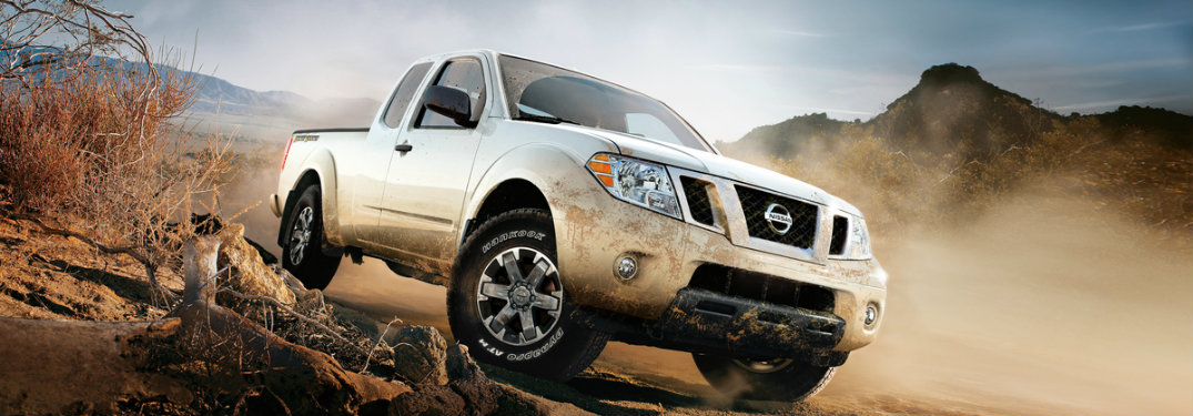 white nissan frontier driving on rocks and dirt