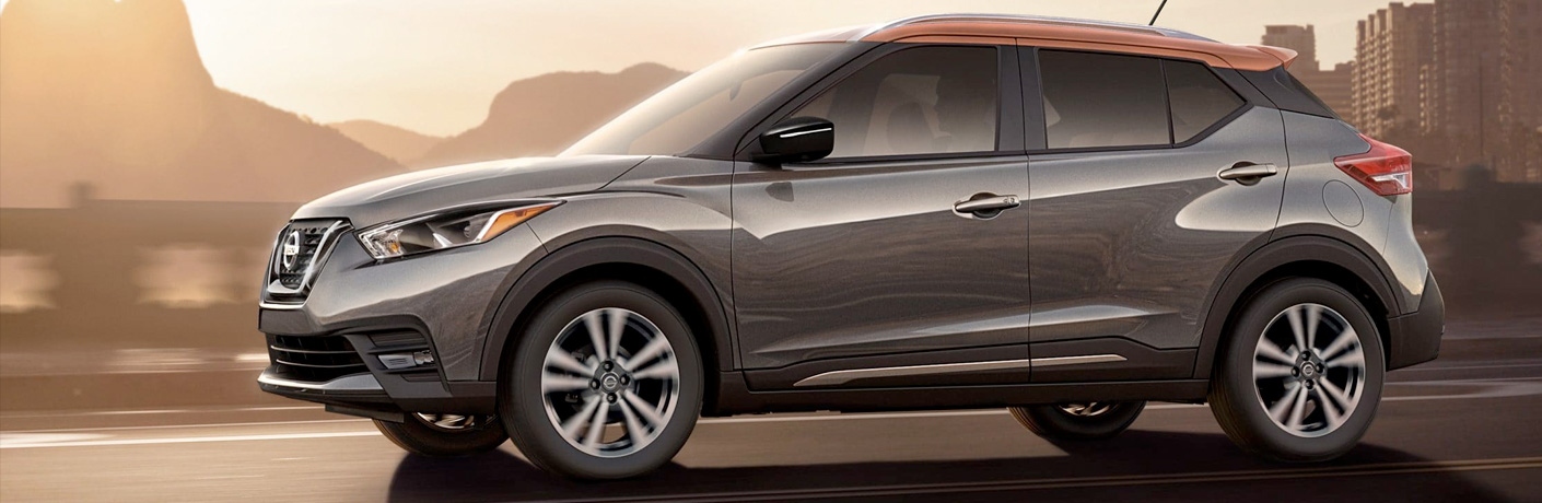Exterior view of a parked grey and orange 2019 Nissan Kicks with mountains in the background
