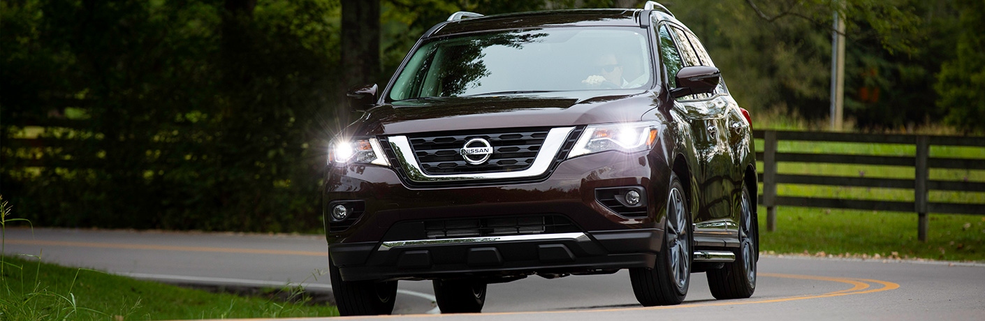 Exterior view of a brown 2019 Nissan Pathfinder driving down a country road