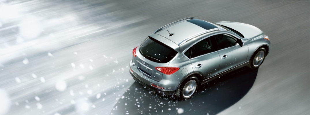 Arial shot of a silver INFINITI SUV driving down a road during heavy snowfall