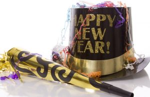 happy new year written on a party hat next to a noise maker