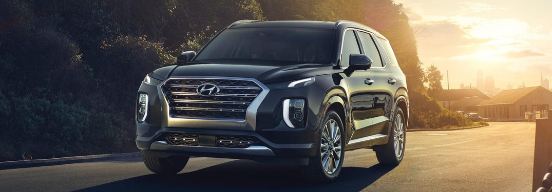 2020 Hyundai Palisade driving down road with trees in background from front drivers side view_o
