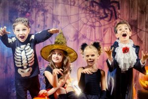 Four kids dressed up for Halloween with pumpkins