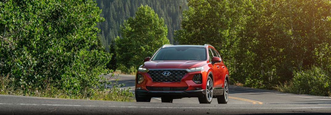 Red 2020 Hyundai Santa Fe driving down road from exterior front view