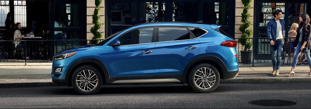 Blue 2020 Hyundai Tucson parked by a sidewalk in a city. Side view.