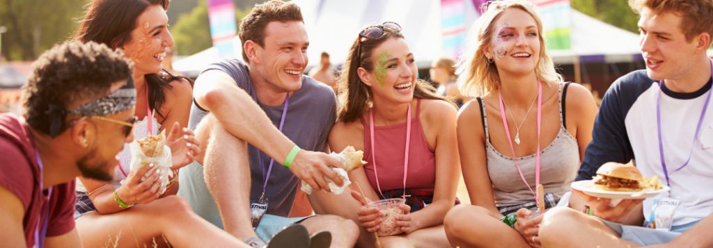 group of friends eating and drinking outdoors at festival
