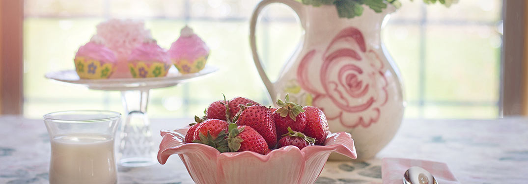 a bowl of strawberries and other attractive porcelain on a table