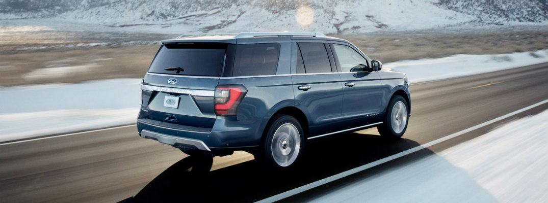 Rear shot of blue 2018 Ford Expedition driving on snowy road